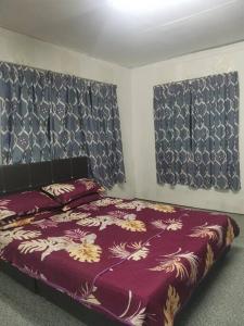 a bedroom with a bed and two windows with curtains at Comfort Stay Kuala Perlis Wi-Fi Nexflix in Kuala Perlis