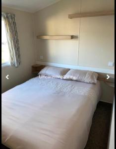a bedroom with a white bed and a window at McCanns Caravan Marton Mere in Blackpool