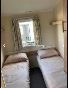 2 camas en una habitación pequeña con ventana en McCanns Caravan Marton Mere, en Blackpool
