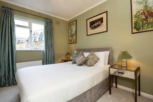 a bedroom with a large white bed and a window at Veeve - Peaceful by Portobello in London