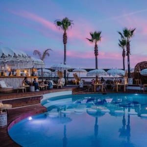 a swimming pool with tables and umbrellas and palm trees at Stunning 3 bed Villa in Vale do Lobo with Resort Membership 3 mins From Beach and Golf in Loulé