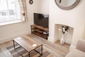 ein Wohnzimmer mit einem TV und einer Vase aus Blumen in der Unterkunft Cosy 2 bed home in Hoole perfect for your Chester break in Chester