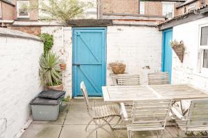 um pátio com uma porta azul, uma mesa e cadeiras em Cosy 2 bed home in Hoole perfect for your Chester break em Chester