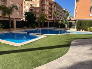 a swimming pool in the middle of a yard with a green lawn at Luxury Penthouse Playas de torrevieja 6pax in Torrevieja