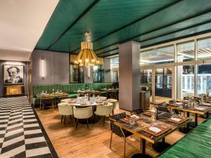 Rixos Gulf Hotel Doha في الدوحة: مطعم بطاولات وكراسي وثريا