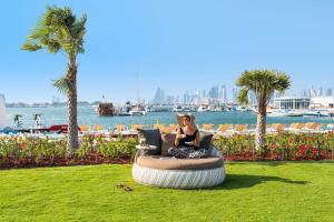 Rixos Gulf Hotel Doha في الدوحة: امرأة جالسة على كرسي كيس فول على العشب