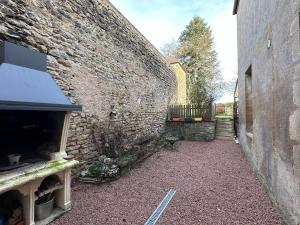 an alley with a stone wall next to a building at Chez Jeanne in Arnay-le-Duc