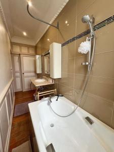 La salle de bains est pourvue d'un lavabo blanc et d'une douche. dans l'établissement L'idylle - Maison & Terrasse, à La Rochelle