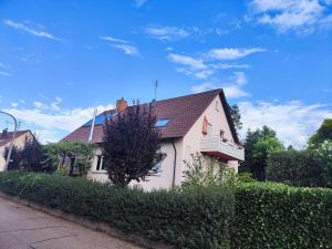 een wit huis met een bruin dak en een heg bij Spatzenbergzimmer 2 in Obersulm