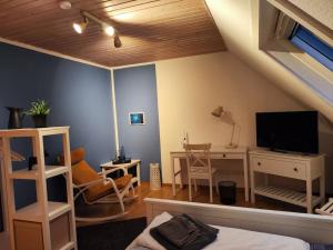 een woonkamer met een bed, een bureau en een televisie bij Spatzenbergzimmer 2 in Obersulm