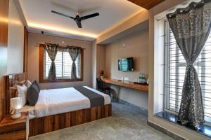 a bedroom with a bed and a desk and windows at OYO Flagship Welcome Premium in Khandagiri