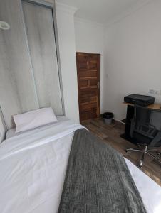 1 dormitorio con 1 cama blanca y TV en Urban oasis in kingsland city en Lusaka