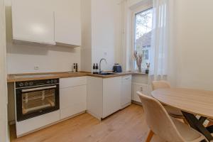 een keuken met witte kasten en een tafel en een raam bij Geräumige Wohnung mit 2 Schlafzimmern in Essen-Stadtwald Nähe Messe Essen in Essen