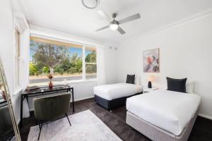 a bedroom with two beds and a desk and a window at Bancroft House on Scenic Mudgee Golf Course in Mudgee