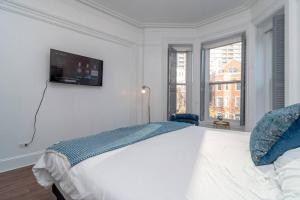 um quarto branco com uma cama e uma televisão na parede em Historical 5 Bedroom Villa that sleeps 12 guests with Patio, Fireplace, Grill and FREE parking em Chicago