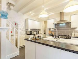 eine große Küche mit weißen Schränken und einem Waschbecken in der Unterkunft 2 Bed in Brixham 86879 in Brixham