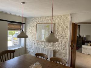 een eetkamer met een tafel en drie hanglampen bij Simple Luxury in Brecon Beacons Village House in Llandovery