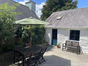 een houten tafel met een paraplu en twee banken bij Simple Luxury in Brecon Beacons Village House in Llandovery