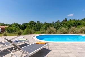 uma piscina com duas cadeiras e uma mesa ao lado em Villa Kristina em Pazin