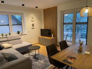 a living room with a couch and a table and a tv at Lake & Town Apartments Klagenfurt in Klagenfurt