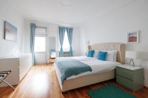 a white bedroom with a large bed with blue pillows at Operastreet City-Center Premium Apartment in Vienna