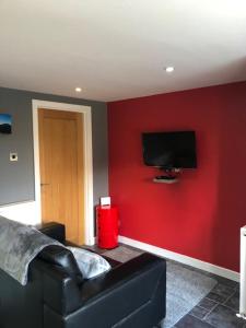 a living room with a red wall with a tv at Minimorn at Ardmorn holiday accommodation in Dunvegan