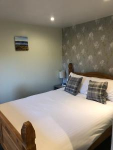 een slaapkamer met een groot wit bed met 2 kussens bij Minimorn at Ardmorn holiday accommodation in Dunvegan