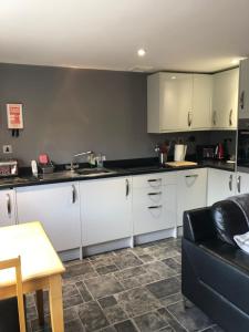 a kitchen with white cabinets and a black counter top at Minimorn at Ardmorn holiday accommodation in Dunvegan