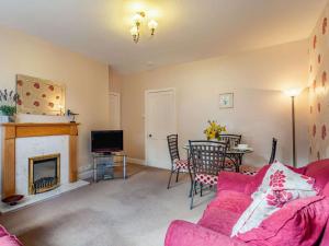 a living room with a pink couch and a fireplace at 2 Bed in Auldearn CA144 in Nairn