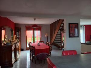 uma sala de jantar com uma mesa vermelha e uma escada em Le Grand Orient em Annoville