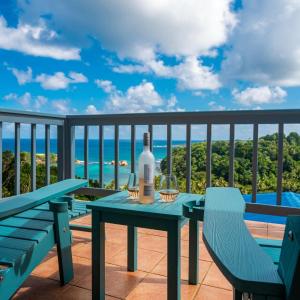 un tavolo con una bottiglia di vino e sedie sul balcone di Hodges Bay House a Calibishie