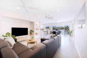 un soggiorno con divano e TV a schermo piatto di 'Infinity's Edge' Darwin Luxury Waterfront Oasis a Darwin