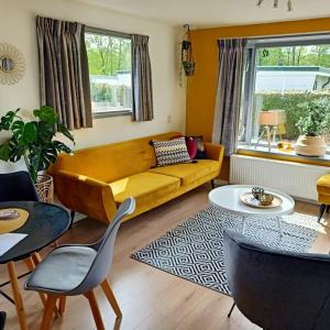een woonkamer met een gele bank en een tafel bij Welkom in Casa du Soleil in Putten