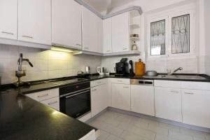 a kitchen with white cabinets and a black stove top oven at Iliokambida house in Corfu +22 photos