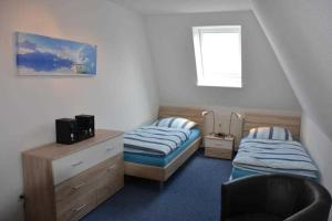 a bedroom with two beds and a chair and a window at _DKK11_ Ferienwohnung Strandburg in Niendorf