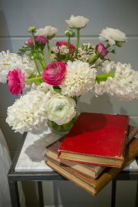 a table with a vase of flowers and books at The Outbuilding Appledore in Snargate