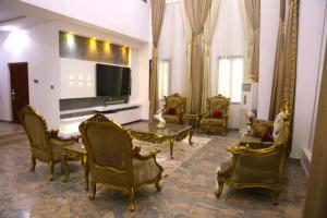 a living room with chairs and a table and a tv at 1164 Residence Apartment in Abuja