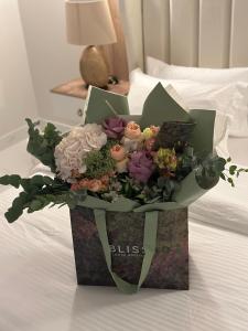 a bouquet of flowers in a box on a bed at شقة حي العقيق قريبة البوليفارد in Riyadh