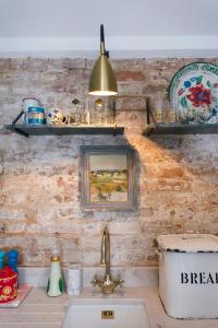 a kitchen counter with a sink and shelves on the wall at The Outbuilding Appledore in Snargate +26 photos
