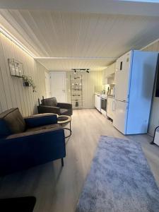 a living room with couches and a white refrigerator at studio apartment with parking in Lillehammer