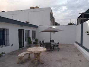 eine Terrasse mit einem Tisch, Stühlen und einem Sonnenschirm in der Unterkunft Amplia Casa Familiar en G Cruz in Godoy Cruz