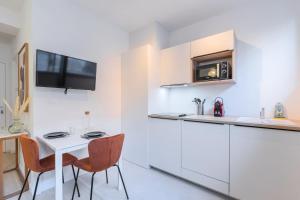 a kitchen with white cabinets and a white table and chairs at Renovated 1 bedroom apartment in Lille