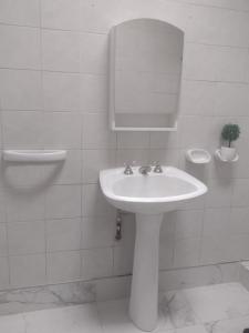 ein weißes Badezimmer mit einem Waschbecken und einem Spiegel in der Unterkunft Amplia Casa Familiar en G Cruz in Godoy Cruz
