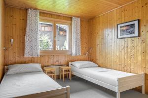 2 Betten in einem Zimmer mit Holzwänden in der Unterkunft Schwarzbueb in Bettmeralp