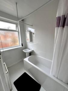 a white bathroom with a tub and a sink at 1 Bedroom flat, Close to All You Need! in Kenton