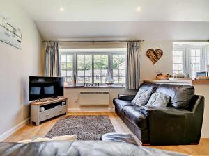 a living room with a leather couch and a flat screen tv at 2 Bed in Perranporth WHHOU in Perranporth