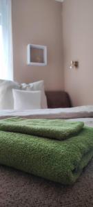 a green blanket sitting on top of a bed at Marianna Apartman Kaposvár in Kaposvár