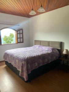 a bedroom with a bed with a purple comforter at Canto dos Pássaros in Nova Friburgo