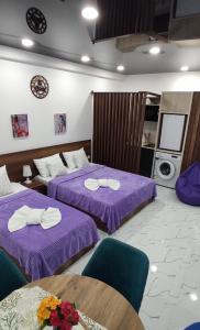 two beds in a room with purple sheets and chairs at Kutaisi Apartment in Kutaisi