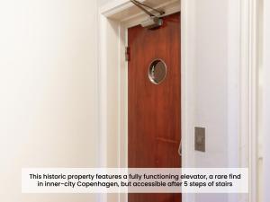 a wooden door in a hallway with a sign next to it at Sanders Monarch - Charming One-Bedroom Apartment With Two Balconies in Copenhagen